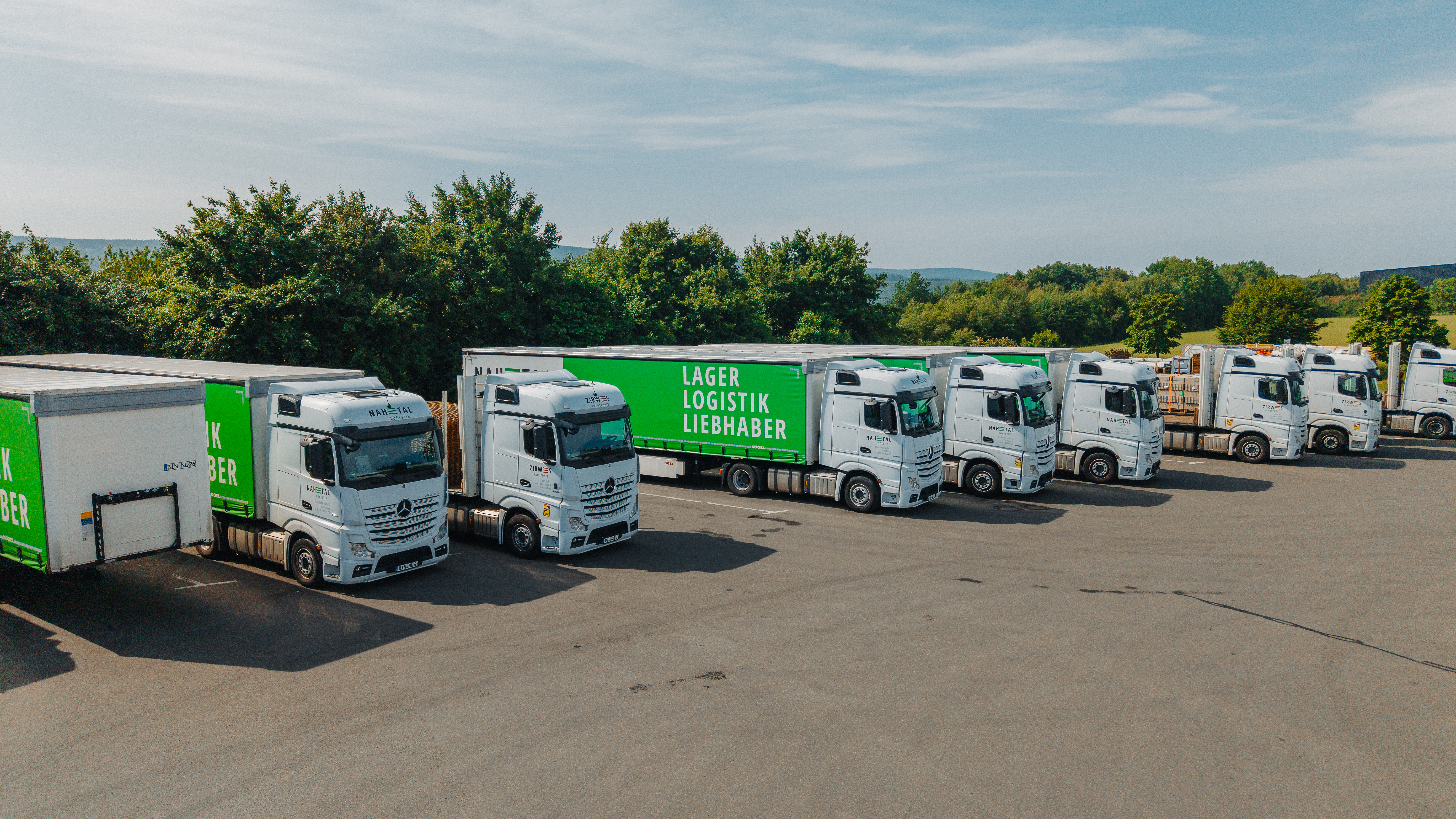 Mehrere LKWs von Nahetal Logistik und Zirwes Transporte stehen nebeneinander geparkt auf dem Hof der Firma.