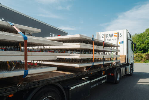 Ein LKW mit der Aufschrift ‚Zirwes Transporte‘ zieht einen beladenen offenen Anhänger.