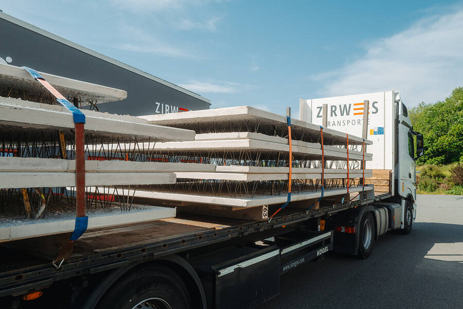 Ein LKW mit der Aufschrift ‚Zirwes Transporte‘ zieht einen beladenen offenen Anhänger.